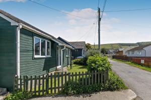a green house with a fence next to a street at 2 Bed in Croyde oc-18lead in Croyde
