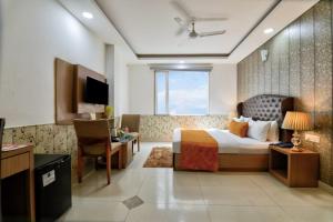 a hotel room with a bed and a television at Hotel Olive Aero Suites By Signature Stayz Near Delhi Airport in New Delhi