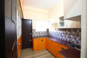 eine Küche mit orangefarbenen Schränken und einer schwarzen Tür in der Unterkunft Sreedevi Residency in Chennai