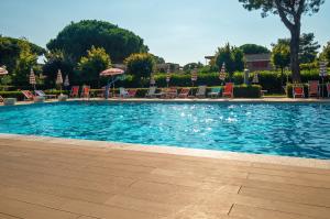 a large swimming pool with chairs and umbrellas at Onde e Relax D&D in Marina di Bibbona