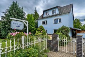 a white fence in front of a blue house at Quartier Sängerstadt in Finsterwalde