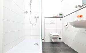 a white bathroom with a shower and a toilet at Gästezimmer ROSS in Hohenlinden +15 photos