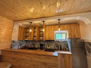a kitchen with wooden cabinets and a stainless steel refrigerator at Горный коттедж in Kobuleti
