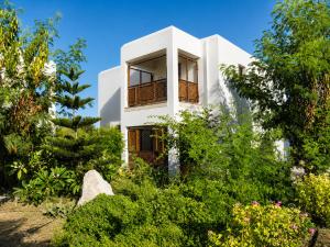 a white house surrounded by trees and bushes at Riviera Beach Bungalows in Kyrenia