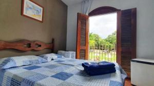 a bedroom with a bed and a large window at Pousada Sant`Ana in Sabará