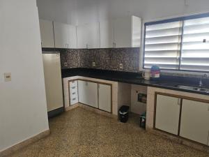 a kitchen with white cabinets and a black counter top at Amplio alojamiento en el centro de Asunción in Asunción