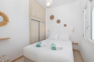 a bedroom with a white bed with slippers on it at Red Beach Harmony suites Modestos in Akrotiri +48 photos