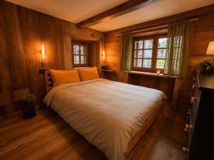 a bedroom with a bed with wooden walls and windows at Casalpina Cozy chalet in Gressoney-la-Trinité