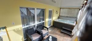 a bathroom with a tub and a chair and a window at Pájer Plázs & Resort in Gyomaendrőd