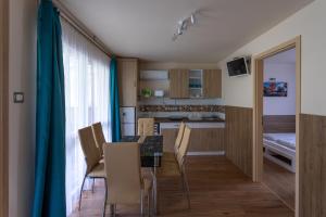 a kitchen and dining room with a table and chairs at Pájer Plázs & Resort in Gyomaendrőd