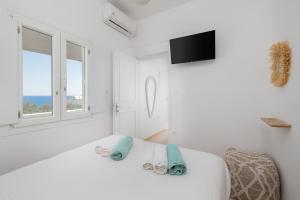 a white room with a bed and two windows at Red Beach Harmony suites Modestos in Akrotiri