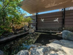 a backyard with a pond with rocks and a building at Hotel Luna Park in Matsuyama