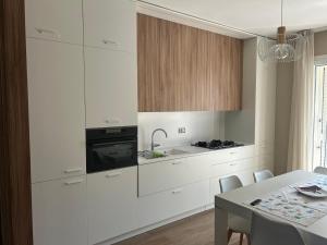 a kitchen with white cabinets and a table with chairs at Maiullari Holiday House in Policoro