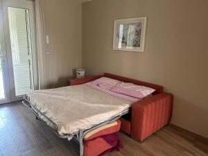 a small bed in a room with a red chair at Maiullari Holiday House in Policoro