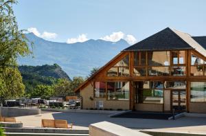 a large wooden building with mountains in the background at Notre Dame Du Laus in Saint-Étienne-le-Laus