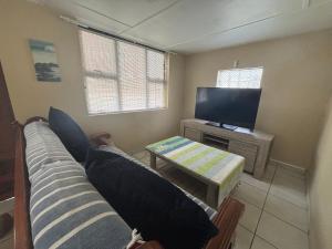 a living room with a couch and a flat screen tv at Siesta Island #5 in Amanzimtoti