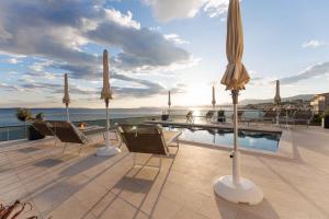 a patio with chairs and umbrellas and a swimming pool at Stella Maris Beach in Podstrana