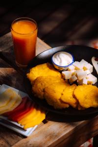 a plate of food on a wooden table with a glass of orange juice at Isla Única- Islas del Rosario in Isla Grande