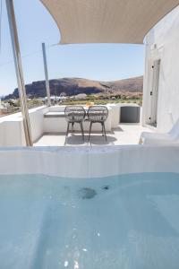 a swimming pool with two chairs and a table at Red Beach Harmony suites Modestos in Akrotiri