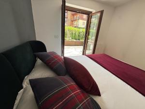 a bedroom with a bed with pillows and a window at Courmayeur 2BR Terrace Mont Blanc View & Parking in Courmayeur