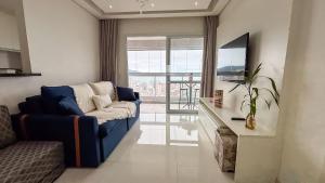 a living room with a blue couch and a television at SHB - Refinement, Ocean View, Sauna and Pool! in Santos