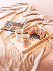 a tray with two cups of coffee and a pastry on a bed at B&B a due passi dal mare in Caulonia Marina