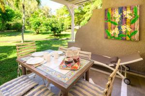 a table and chairs on a patio with a painting at Beachfront Duplex with Estate Pool in Bain Boeuf +12 photos