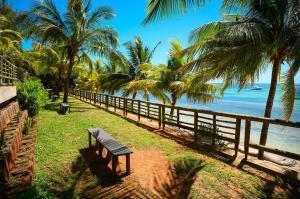 a bench sitting on the grass near the beach at Beachfront Duplex with Estate Pool in Bain Boeuf