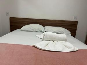 a bed with white sheets and pillows on it at Flat no centro VDP314 - Rooftop in Porto De Galinhas