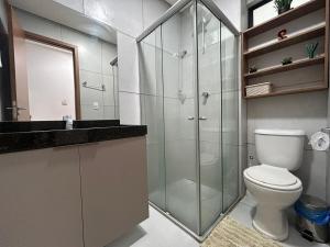 a bathroom with a toilet and a glass shower at Flat no centro VDP314 - Rooftop in Porto De Galinhas +8 photos