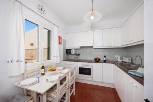 a kitchen with white cabinets and a table with chairs at Villa Gelabert Ametller in Cala en Bosc