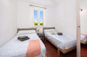 a bedroom with two beds and a window at Villa Gelabert Ametller in Cala en Bosc +9 photos
