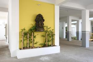 eine Statue an einer gelben Wand mit Pflanzen in der Unterkunft Sreedevi Residency in Chennai