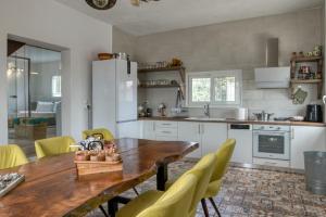 a kitchen with a wooden table and yellow chairs at Sahara Blanc Villa - Private Pool - Loft Space in Spiliazéza