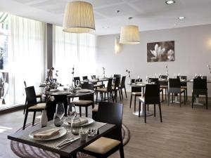 a dining room with tables and chairs and windows at ibis Styles Chalon sur Saône in Chalon-sur-Saône