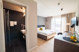 a hotel room with a bed and a bathroom at Hotel Garni Maximilian in Dingolfing