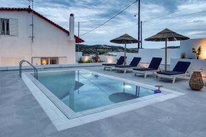 a pool with chairs and umbrellas next to a house at Sahara Blanc Villa - Private Pool - Loft Space in Spiliazéza