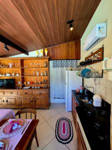 a kitchen with wooden cabinets and a table and a refrigerator at Luz Residence suíte in Cabo Frio