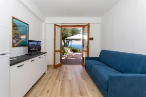 a living room with a blue couch and a television at Paradise Residence Garden in SantʼAlessio Siculo