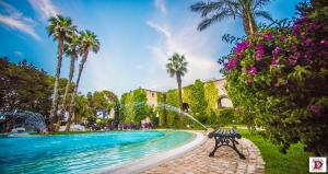 a bench next to a swimming pool with palm trees at Relais Reggia Domizia in Manduria