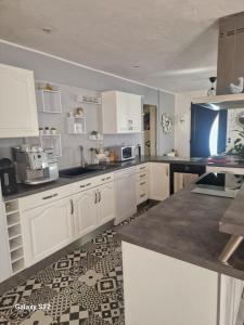 a kitchen with white cabinets and a tile floor at Maison de campagne à Balaives et Butz in Flize +7 photos