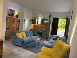 a living room with a blue couch and yellow chairs at Apartmán Sebina s vinným sklípkem in Drnholec