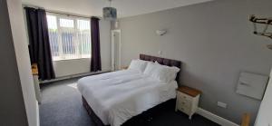 a bedroom with a bed with white sheets and a window at Moon Tap Hideaway in Bridlington