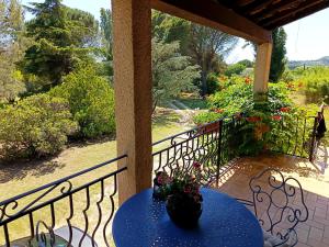 a table on a porch with a view of a garden at Mas de la Croix - Chambres d'hôtes in Sernhac
