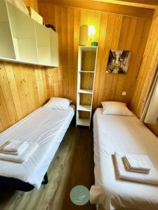two twin beds in a room with wooden walls at CHALET SUR PILOTIS - 4 personnes - CLIMATISÉ- PISCINE- PROCHE PLAGE in Arès