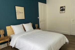 a bedroom with a large white bed with a blue wall at La maisonnette 70' in Groseillier