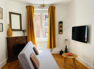 a living room with a white couch and a television at La maisonnette 70' in Groseillier