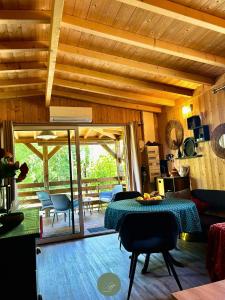 a living room with a table and a dining room at CHALET SUR PILOTIS - 4 personnes - CLIMATISÉ- PISCINE- PROCHE PLAGE in Arès