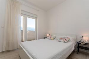 a white bedroom with a bed and a window at Apartment Sankovic in Ražanac