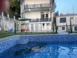 a house and a swimming pool in front of a house at BlueWave Villa in Kangra